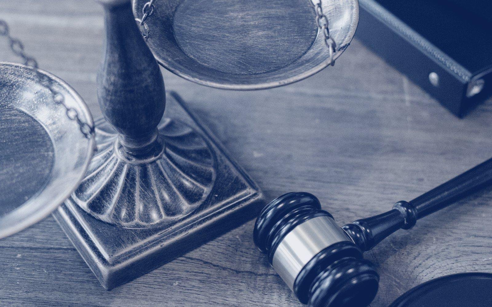 Balanza de la justicia y mazo sobre un escritorio de madera junto a expedientes